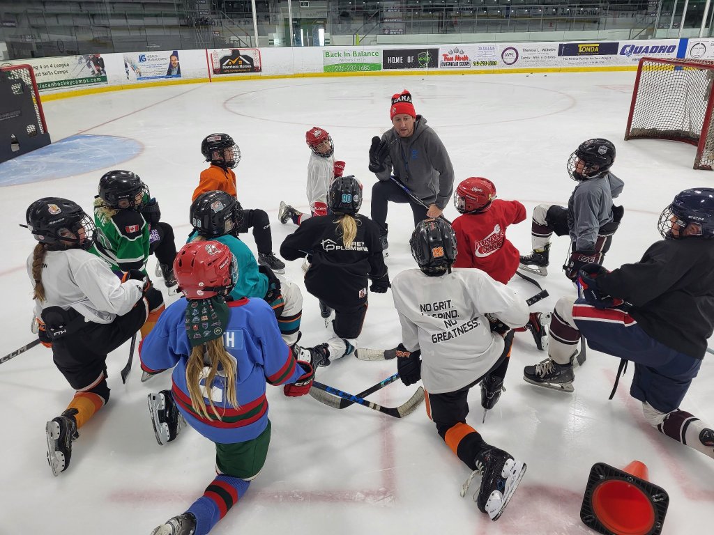 GRIT Hockey coach with young players gathered in a huddle on the ice